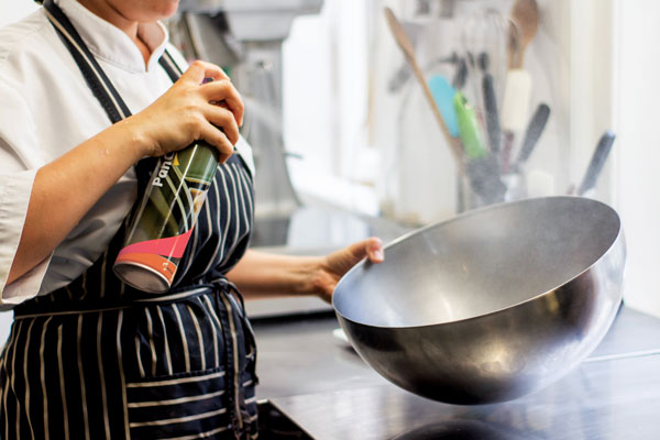Photo of a chef spraying something into a large mixing bowl.