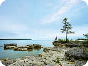 Door County Wisconsin. Destination Door County. Outside view of a woman standing on rocks overlooking the lake.