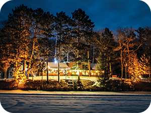 On the Cover. Pitlik's Sand Beach Resort, Eagle River, WI. Exterior nighttime photo of the property surrounded by trees taken from an ice covered lake.